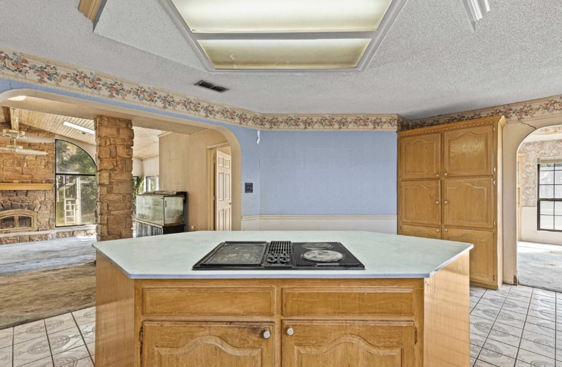 Kitchen — cooktop island and living room opening · Before renovation · Longview, Texas